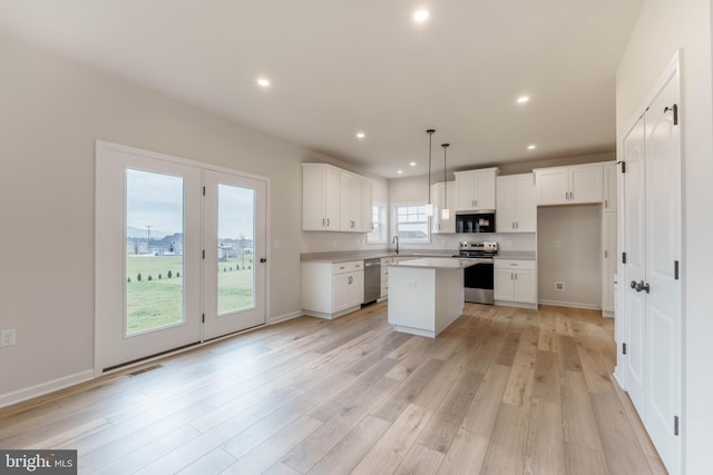 kitchen featuring a kitchen island, sink, white cabinetry, hanging light fixtures, and appliances with stainless steel finishes