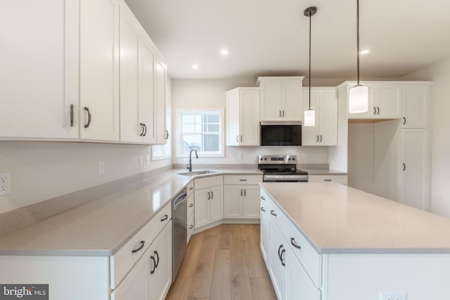 kitchen with decorative light fixtures, a center island, sink, stainless steel appliances, and white cabinets