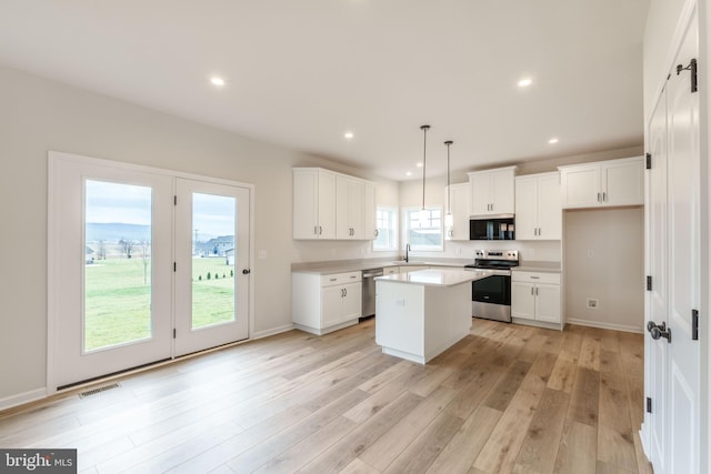 kitchen featuring white cabinetry, stainless steel appliances, hanging light fixtures, a kitchen island, and sink