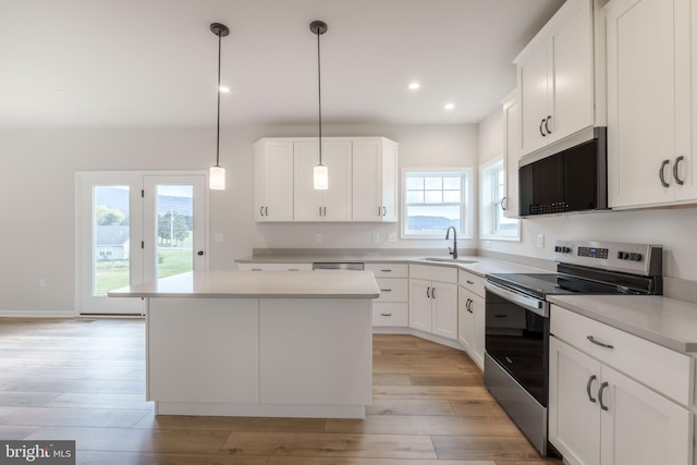 kitchen with pendant lighting, a center island, white cabinetry, electric stove, and sink