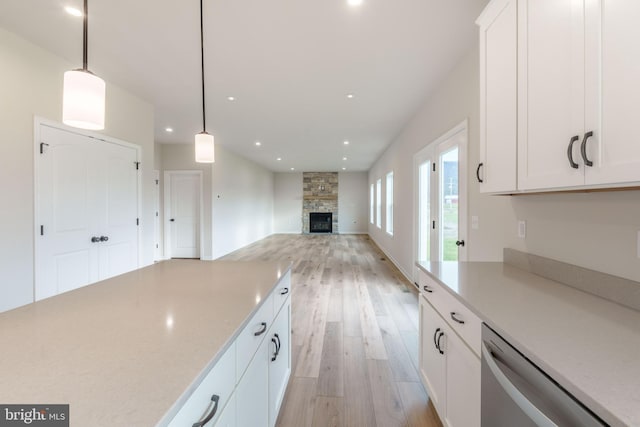 kitchen with decorative light fixtures, white cabinets, dishwasher, and a fireplace