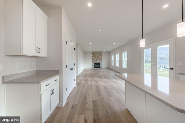 kitchen with decorative light fixtures, white cabinets, and a fireplace