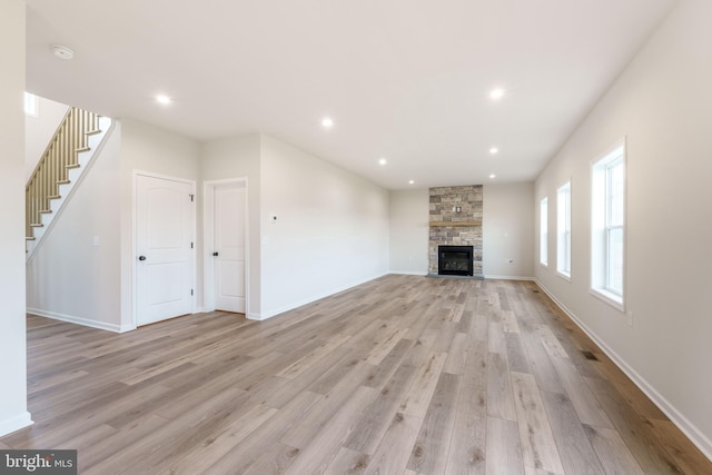 unfurnished living room with light hardwood / wood-style floors and a stone fireplace