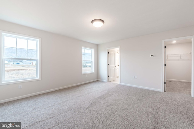 unfurnished bedroom with light colored carpet, a closet, and a walk in closet