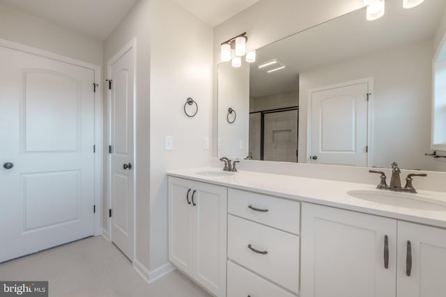 bathroom with a shower with door, vanity, and tile patterned flooring