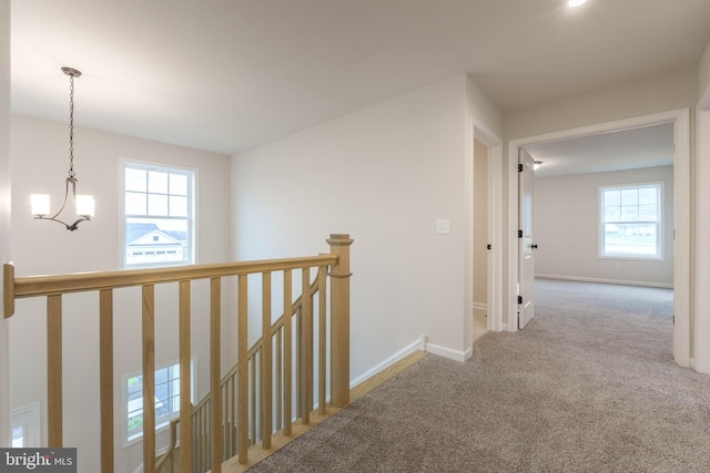 hallway with light carpet and a chandelier