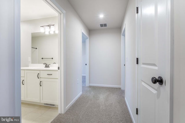 corridor featuring light carpet and sink