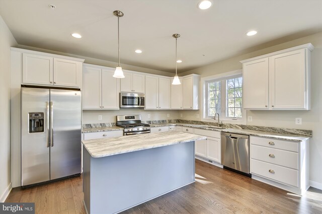 kitchen featuring pendant lighting, white cabinetry, stainless steel appliances, and light hardwood / wood-style floors