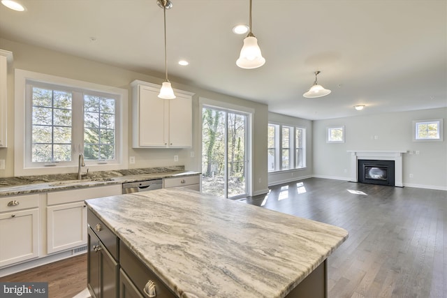 kitchen featuring hanging light fixtures, white cabinetry, sink, and light stone counters