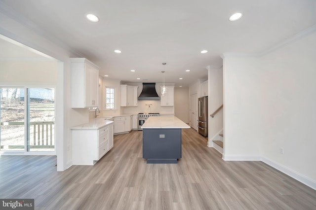 kitchen with white cabinetry, custom exhaust hood, decorative light fixtures, high end appliances, and a kitchen island