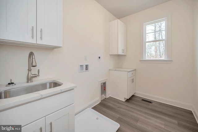 washroom with hardwood / wood-style flooring, hookup for an electric dryer, washer hookup, cabinets, and sink