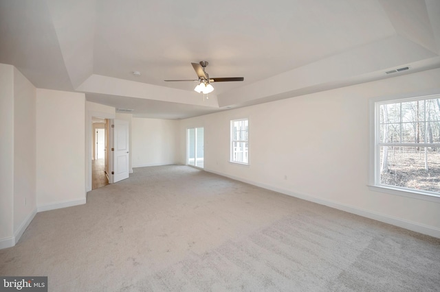 carpeted empty room with ceiling fan and a raised ceiling