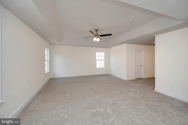 carpeted spare room with ceiling fan and a raised ceiling