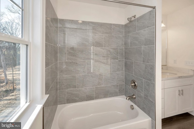 bathroom with a wealth of natural light, tiled shower / bath combo, vanity, and hardwood / wood-style floors