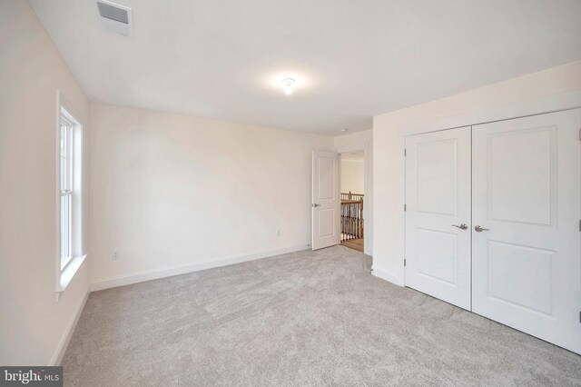 unfurnished bedroom featuring light colored carpet and a closet