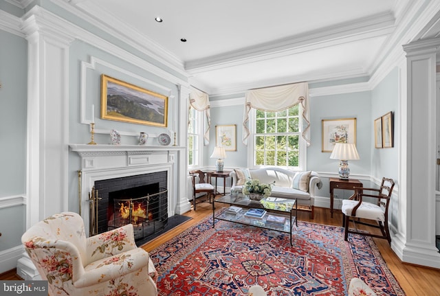 living room featuring light wood-type flooring, a fireplace, and crown molding