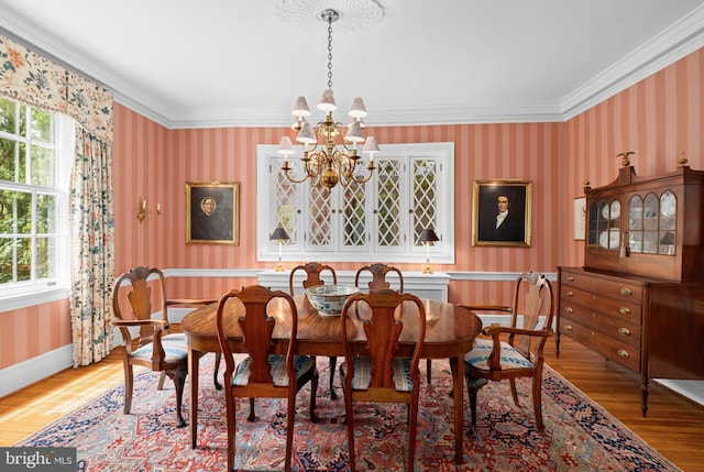 dining space featuring hardwood / wood-style floors, ornamental molding, and an inviting chandelier