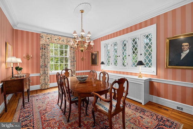 dining area with ornamental molding, hardwood / wood-style flooring, and a notable chandelier