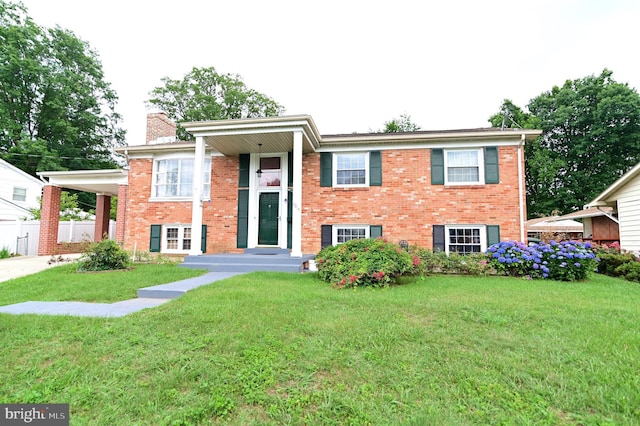 raised ranch with brick siding, a front lawn, a carport, and driveway