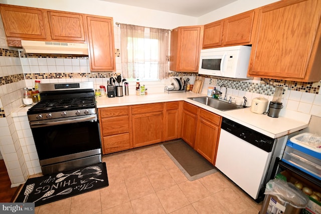 kitchen featuring under cabinet range hood, white appliances, light countertops, and a sink