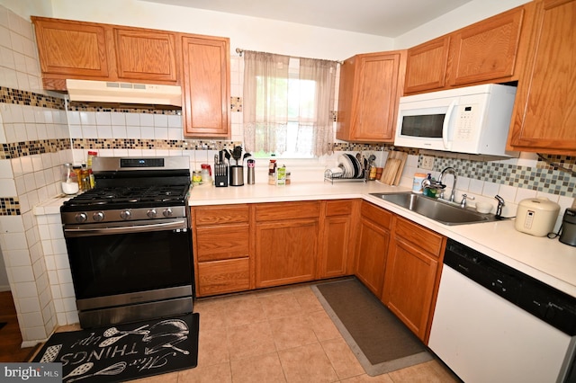 kitchen with under cabinet range hood, white appliances, light countertops, and a sink