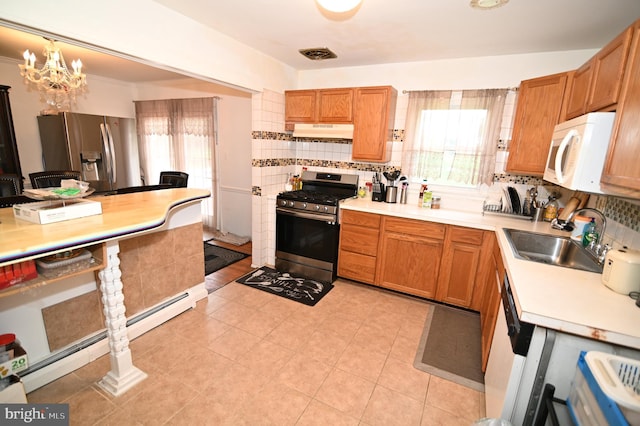 kitchen with a sink, decorative backsplash, under cabinet range hood, appliances with stainless steel finishes, and a baseboard heating unit