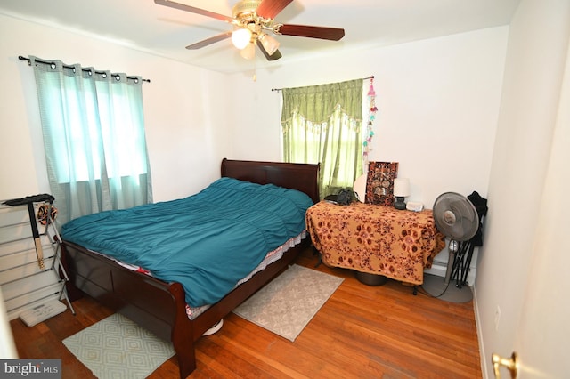 bedroom with ceiling fan, multiple windows, and wood finished floors