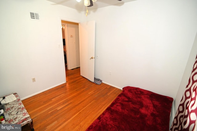 bedroom featuring ceiling fan, visible vents, baseboards, and wood finished floors