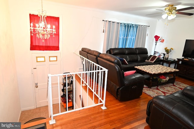 living area featuring wood finished floors, crown molding, and ceiling fan with notable chandelier