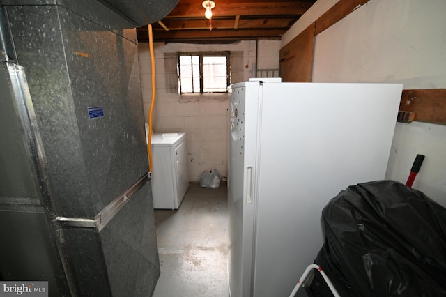 below grade area featuring heating unit, washer / dryer, concrete block wall, and freestanding refrigerator