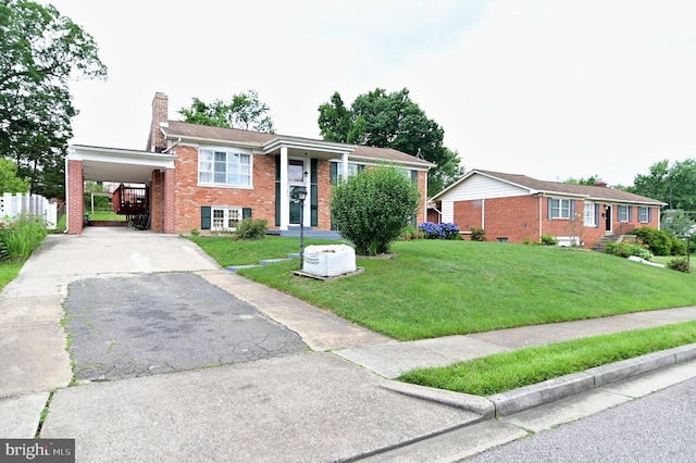 view of front of house featuring brick siding, an attached carport, aphalt driveway, and a front yard