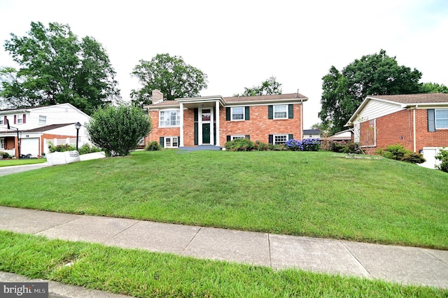 raised ranch featuring a front lawn, brick siding, and a chimney