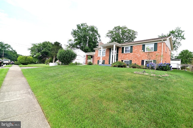 split foyer home featuring brick siding and a front lawn