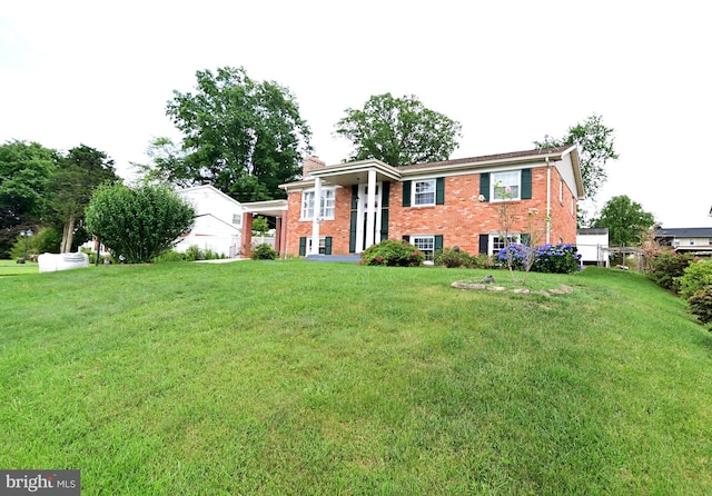 raised ranch with an attached carport, brick siding, and a front yard