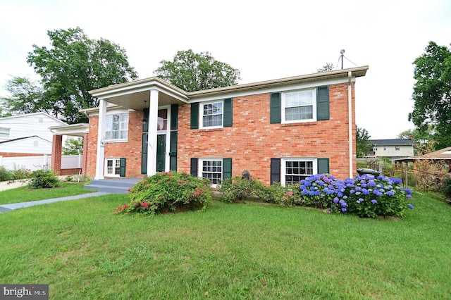 split foyer home featuring a front yard, fence, and brick siding