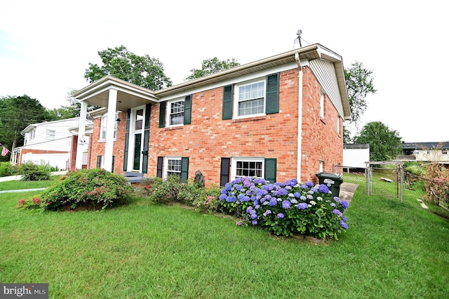 split foyer home with fence, brick siding, a front lawn, and a gate