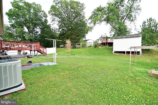 view of yard featuring an outdoor structure, central air condition unit, and a wooden deck