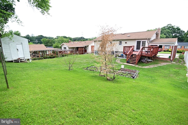 view of yard with a storage unit, an outbuilding, a deck, and fence