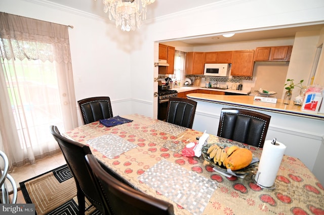 dining space featuring light tile patterned floors, a chandelier, and ornamental molding