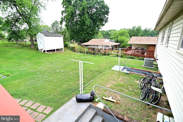 view of yard featuring a storage shed, central AC, fence, and an outdoor structure