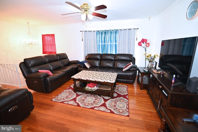 living area featuring wood finished floors, a ceiling fan, and crown molding