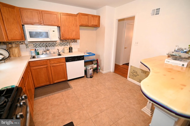 kitchen with white appliances, light countertops, visible vents, and a sink