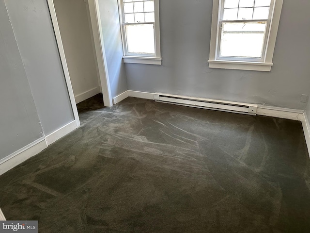 carpeted spare room with a baseboard heating unit