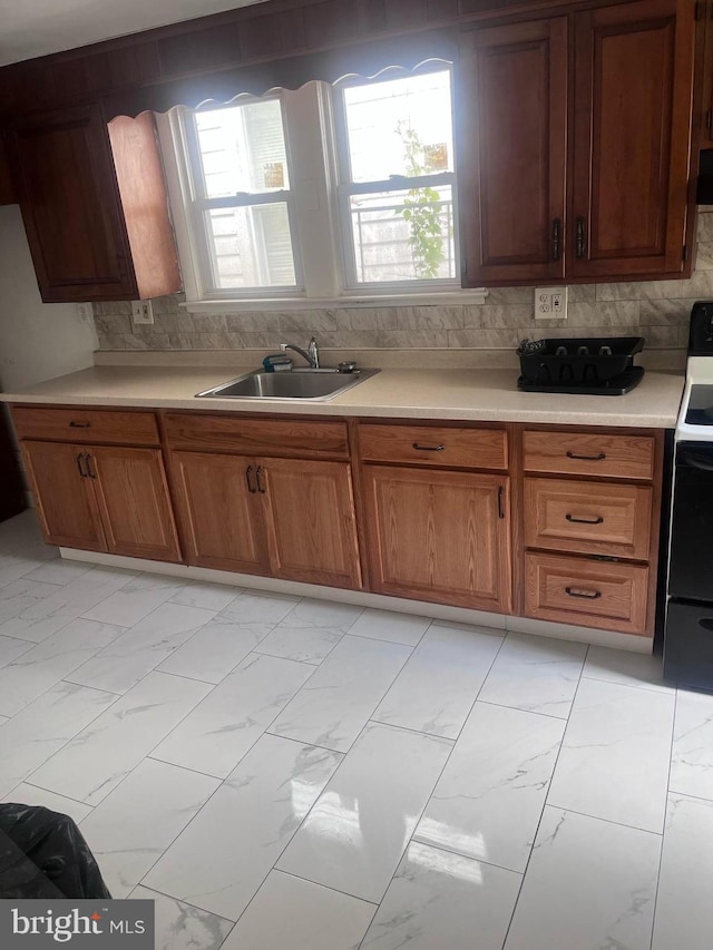 kitchen with range, sink, tasteful backsplash, and a healthy amount of sunlight