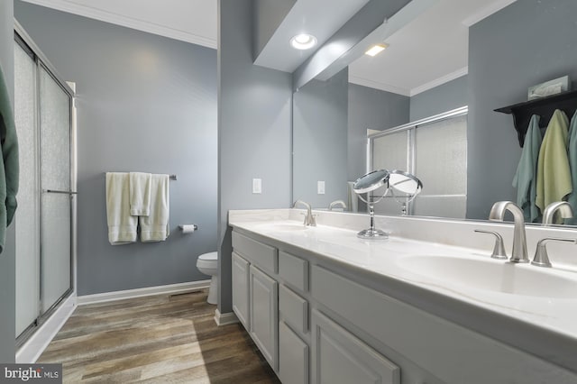 bathroom featuring a shower with shower door, wood-type flooring, vanity, toilet, and crown molding