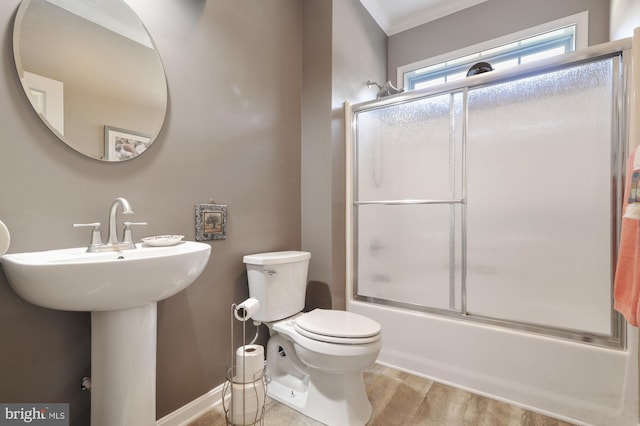 full bathroom with bath / shower combo with glass door, hardwood / wood-style floors, sink, ornamental molding, and toilet