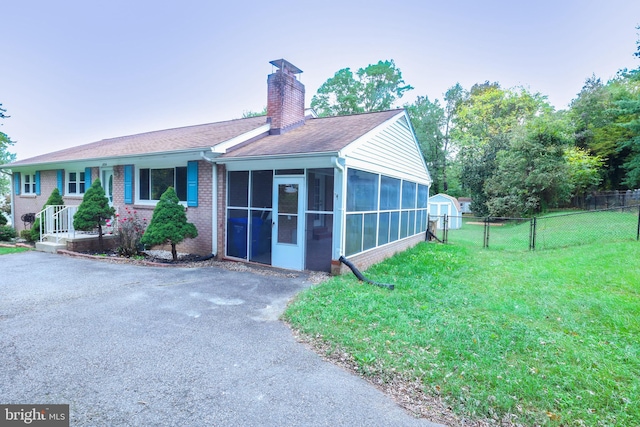 view of front of house featuring a front yard, a sunroom, and a shed