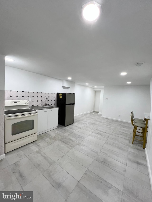 kitchen featuring white cabinets, white electric stove, sink, backsplash, and stainless steel refrigerator