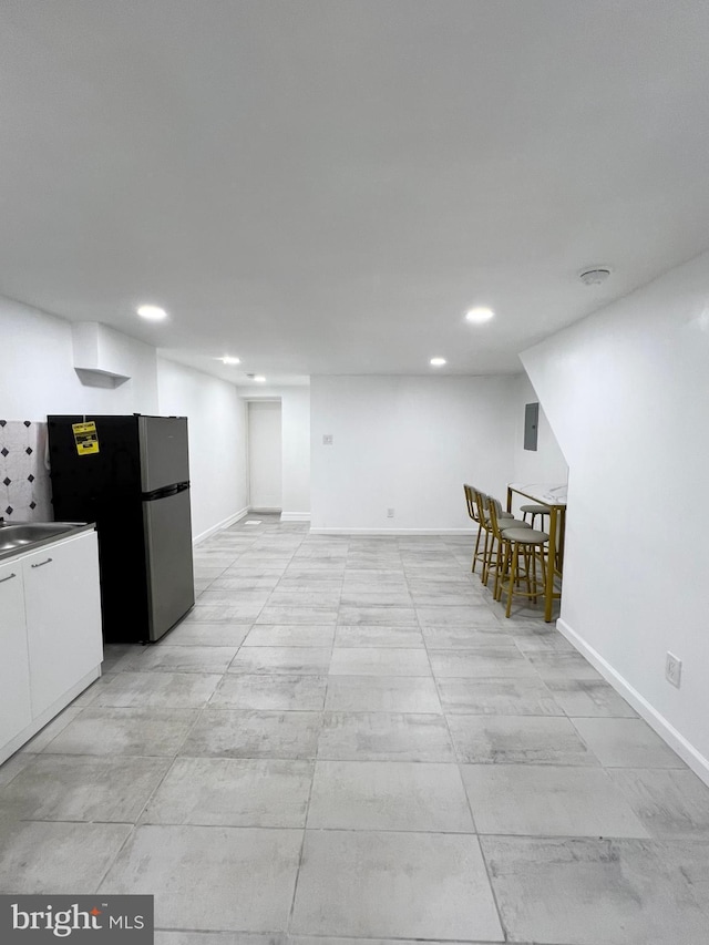 interior space with electric panel, white cabinetry, and stainless steel refrigerator