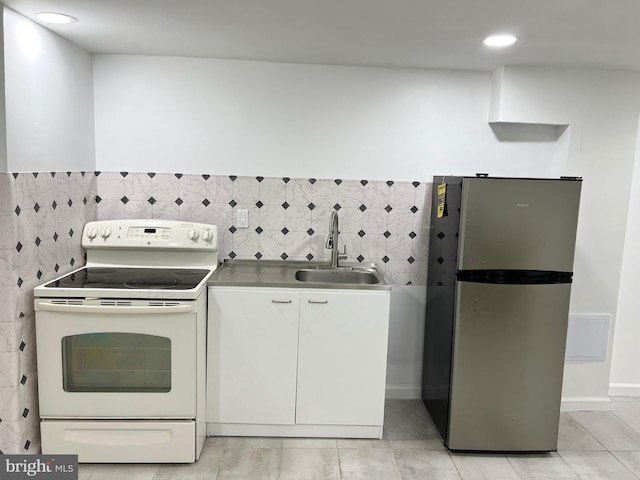 kitchen with white cabinetry, sink, stainless steel fridge, and electric stove